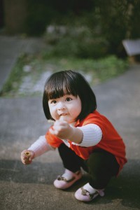 台北兒童寫真，小女孩坐在地上拿了東西伸向鏡頭