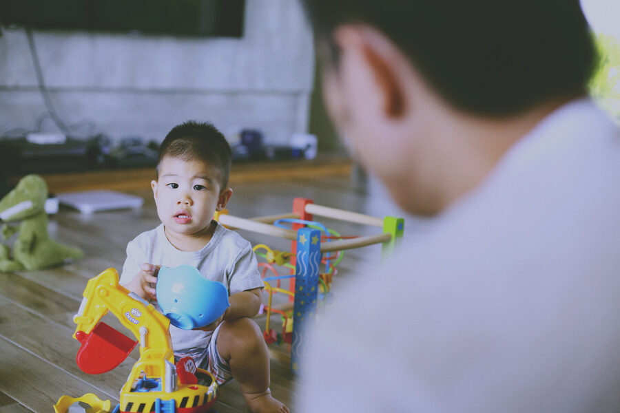 台北親子寫真，小男孩坐在地上玩玩具挖土機，爸爸在一旁陪伴